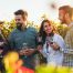 two men and two women standing in front of vineyard holding wine glasses
