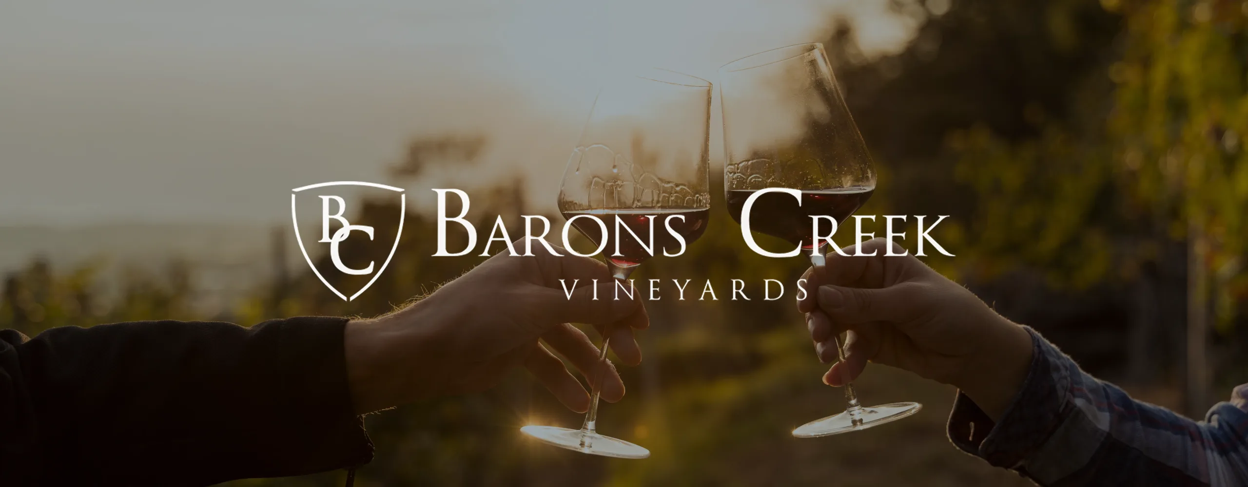 Barons Creek Vineyards logo on an image of two people clinking wine glasses.