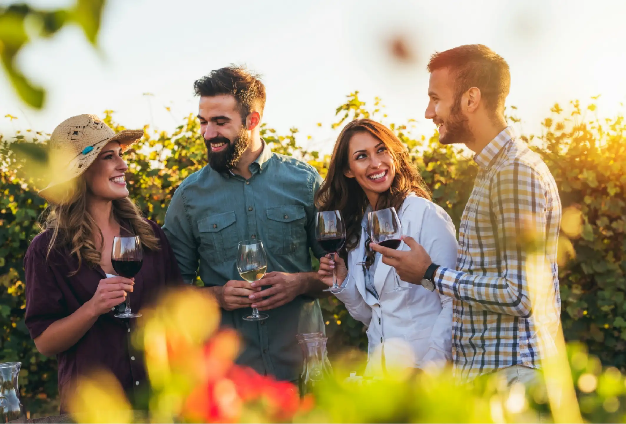 Four friends standing outside, enjoying wine in a beautiful setting.