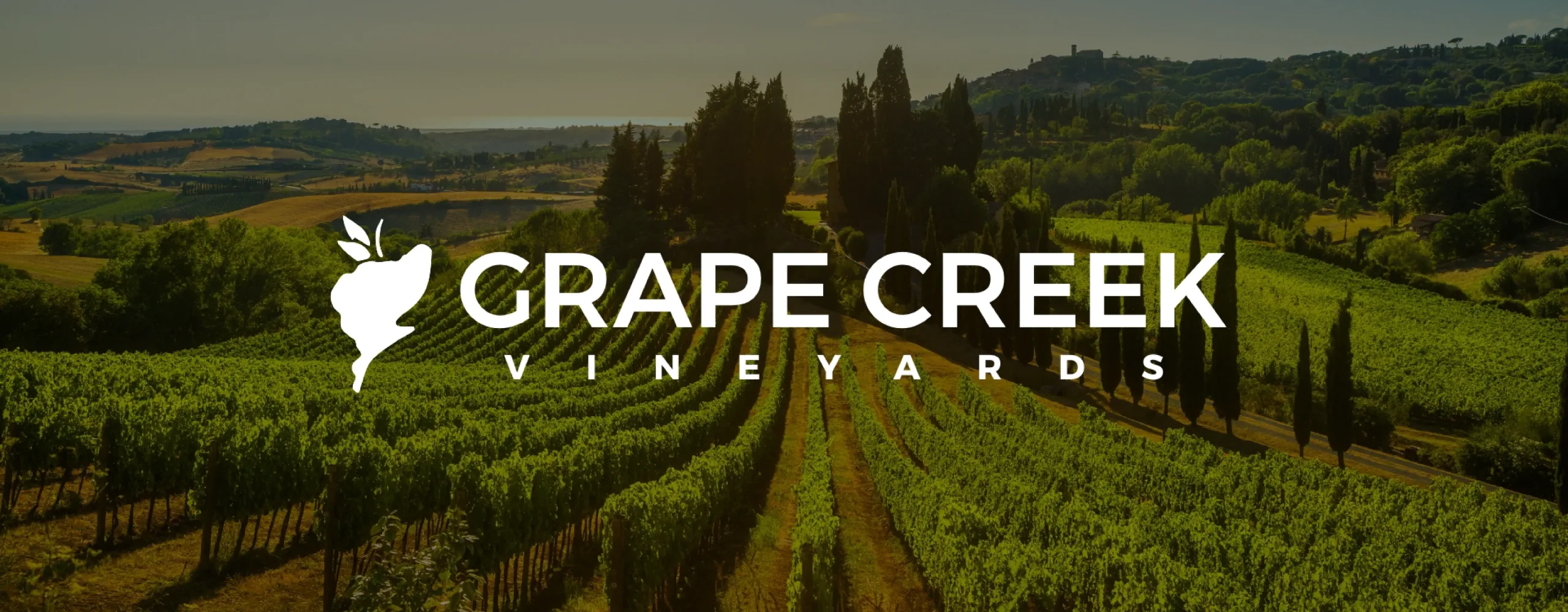 Logo of Grape Creek Vineyards overlaid on a photo of a vineyard.