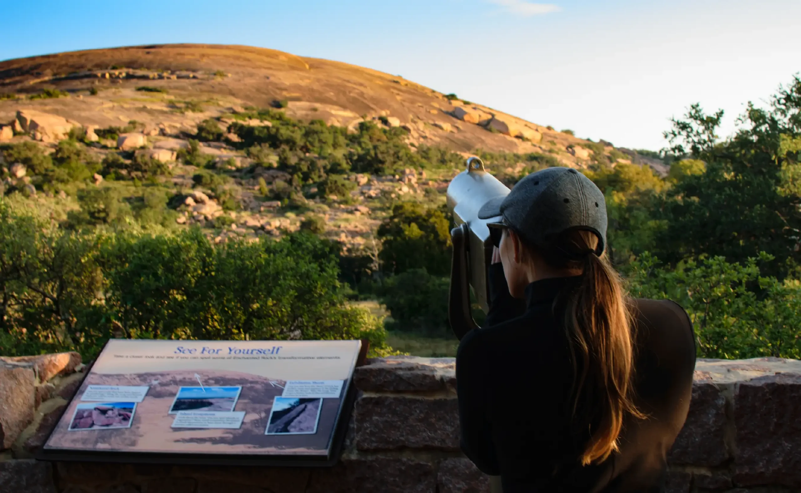 A young woman wearing a ball cap looks at scenery in Fredericksburg, Texas.